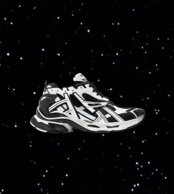 Black and white Balenciaga Runners with a layered, chunky sole set against a black, star-filled background.
